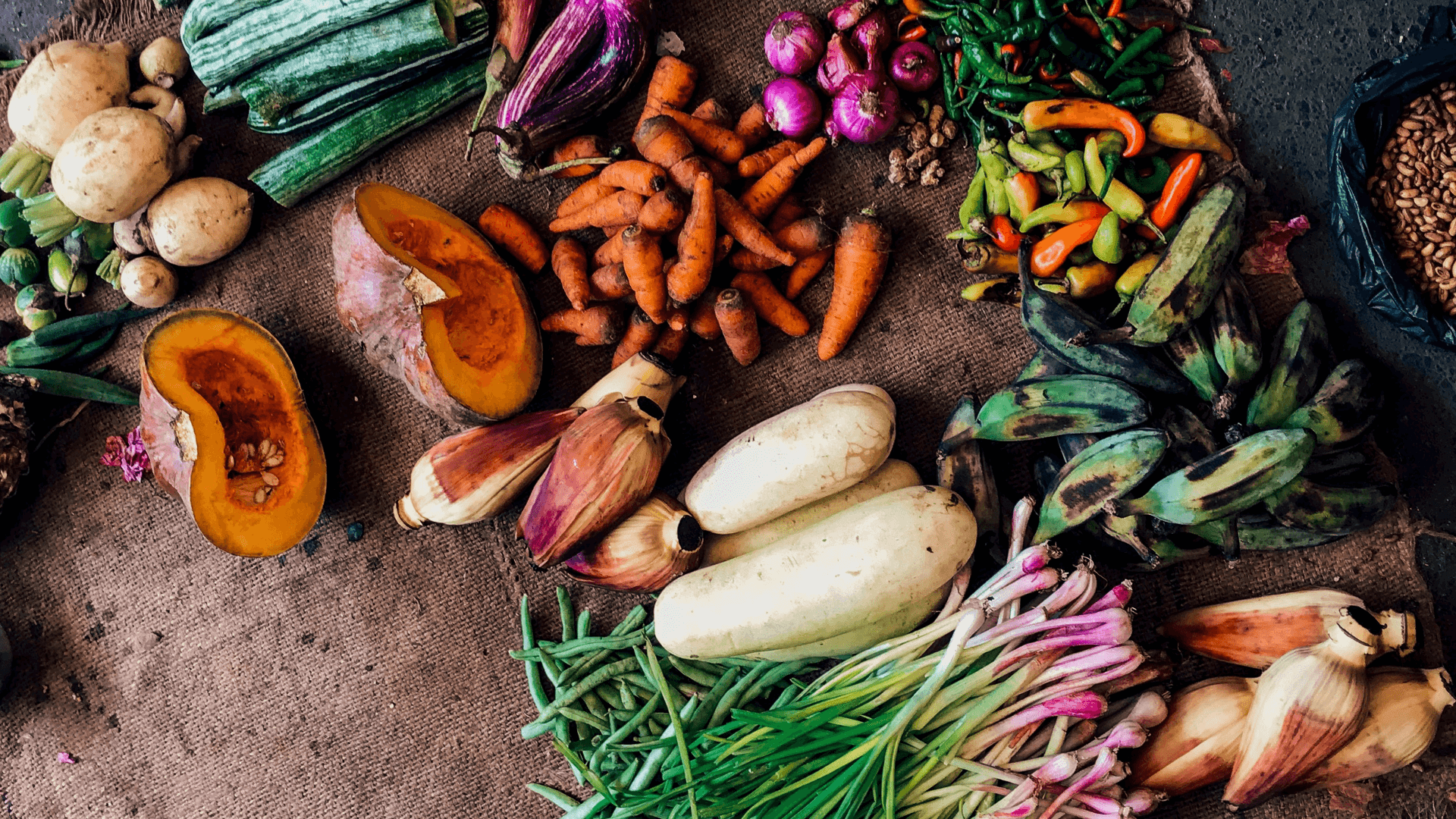 Older colourful veggies on a brown potato sack.