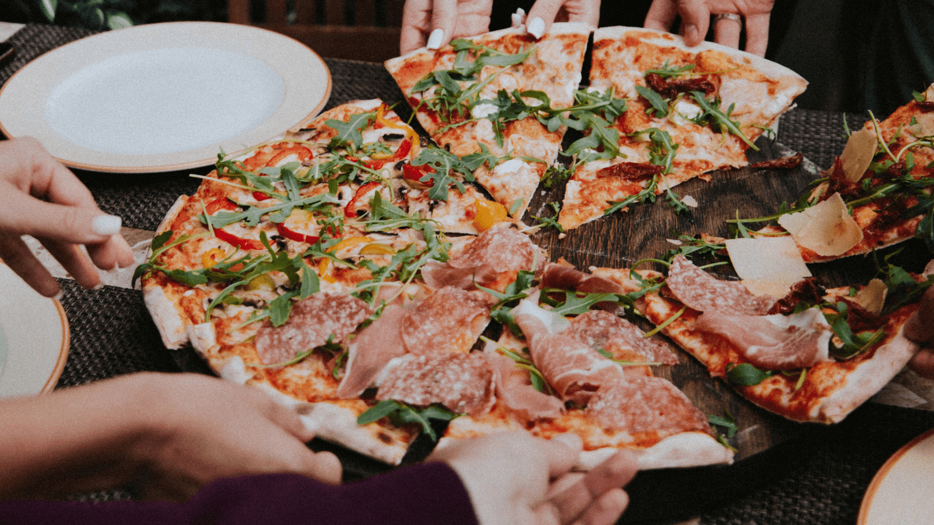 A group of friends each take a slice of pizza.