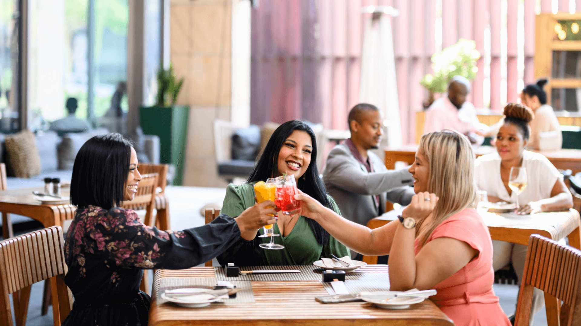 Three women sitting at a table with cocktails.