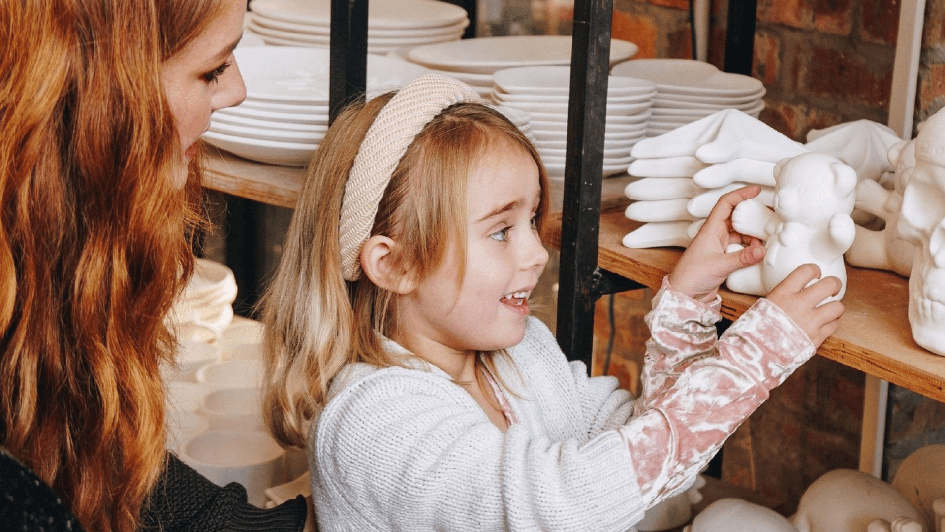 A young girl holds a ceramic teddy bear.