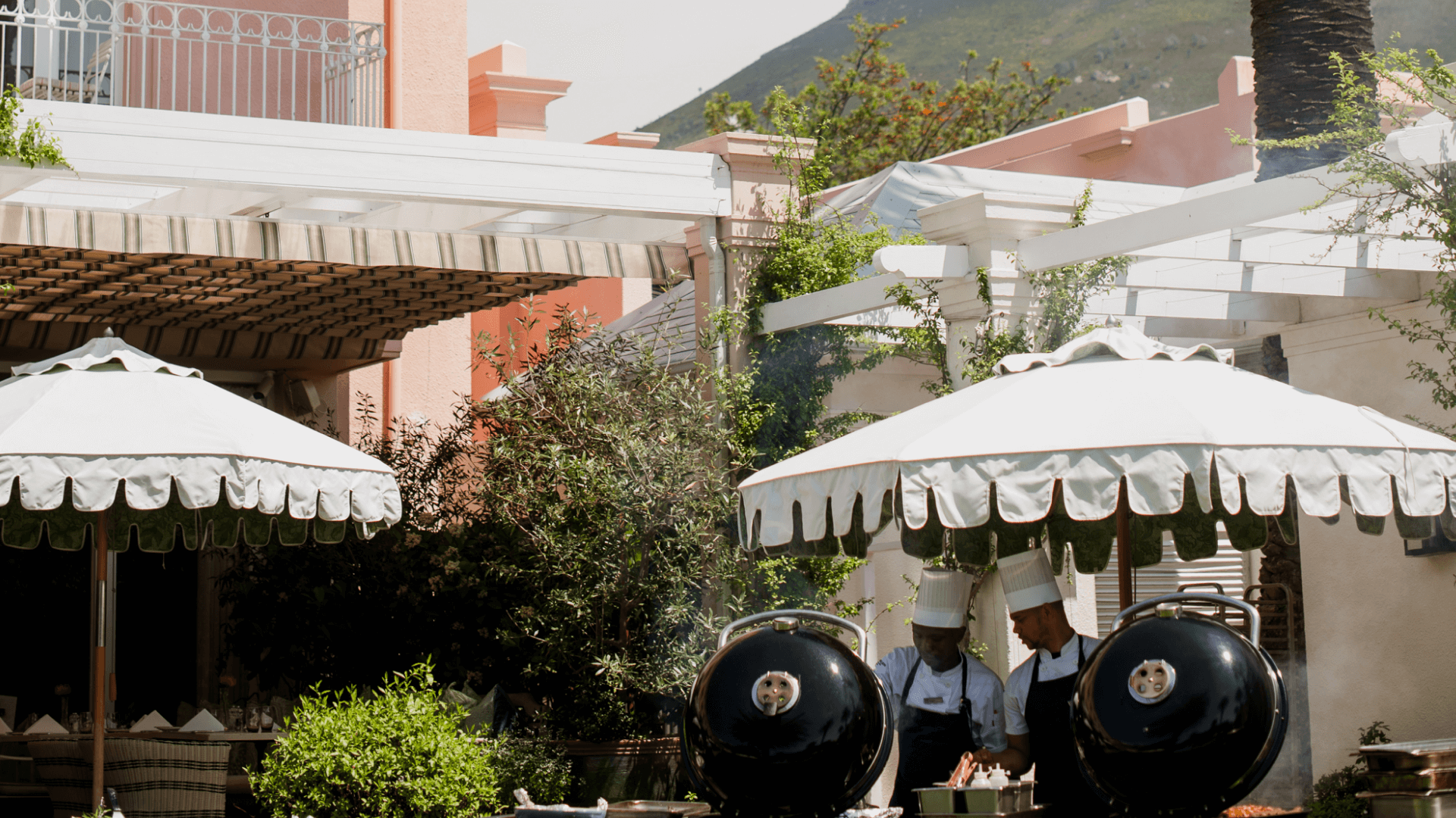 two men braaing at Oasis at the Mount Nelson under white umbrellas,