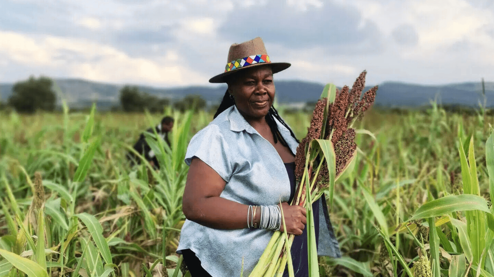 Storytellers redefining african cuisine Siphiwe stands amongst tall grass, holding a bunch of what looks like wheat in her hands.